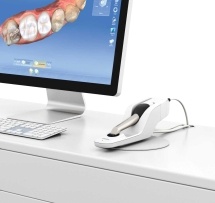 Dental camera on a desk next to computer screen showing model of teeth