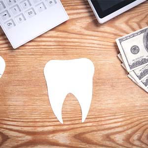 Cutout of tooth resting on a table next to money