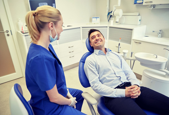 man in dental chair smiling at his emergency dentist in Houston 