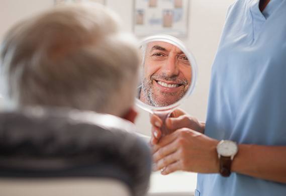 older man admiring his smile in the mirror