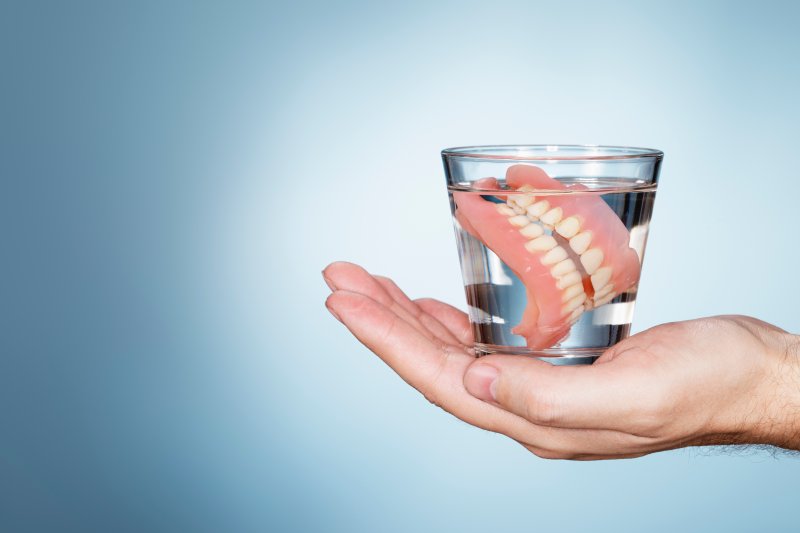 person holding a cup and caring for dentures in Houston